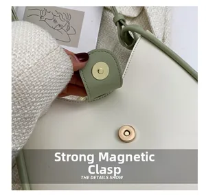 Detail of strong golden magnetic buckle on cream and green contrast shoulder bag