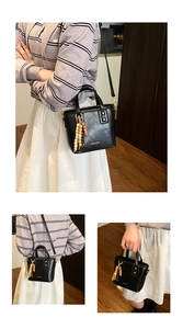 Détail du sac seau trapèze noir avec pendentif perlé et bandoulière amovible