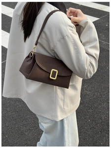 Macro shot of dark brown matte leather handbag with elegant rectangular gold metal buckle