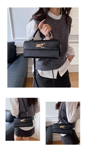 Detail of classic black leather handbag with gold buckle closure and adjustable strap