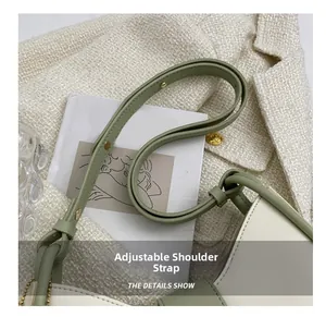 Detail showing the adjustable green shoulder strap of a stylish contrast crossbody bucket bag