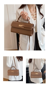 Macro view of textured brown leather and elegant light gold metal twist lock on flap bag