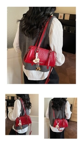 Detail of red glossy leather shoulder bag with floral pendant and embossed fashion logo