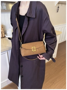 Detailed view of a brown textured crossbody bag with a gold square metal clasp decoration