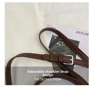 Détail d'une bandoulière réglable en cuir grainé marron foncé avec boucle argent