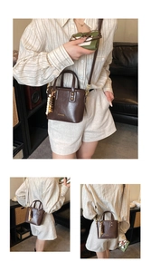 Détail du sac seau en cuir marron foncé avec lettrage doré et pompon en perles