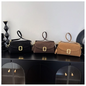 Detailed view of three minimalist suede shoulder bags with gold rectangular metal buckles