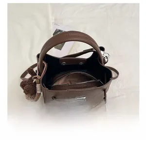 Vue de dessus du sac seau marron à motif litchi avec poche zippée et breloque ours en peluche