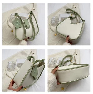 Detail view of contrast color crossbody bucket bag with elegant floral charm and flap closure