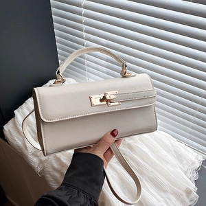 Macro shot of cream trapezoid handbag showing gold twist lock and crossgrain leather