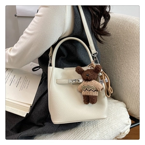 Détail du sac seau en cuir grainé blanc avec boucle argentée et breloque ours en peluche