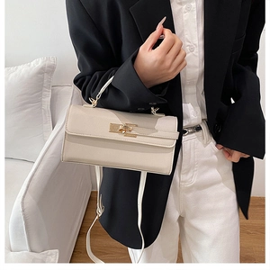 Detail of cream white litchi pattern leather handbag with gold twist lock and shoulder strap