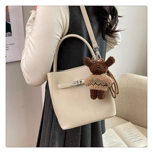 Détail du sac seau blanc cassé en cuir grainé avec boucle et breloque ours en peluche