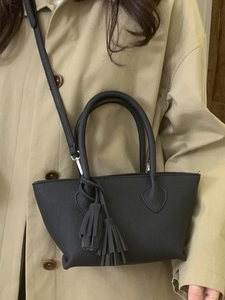 Minimalist black trapezoid handbag with leather tassels and crossbody strap detail