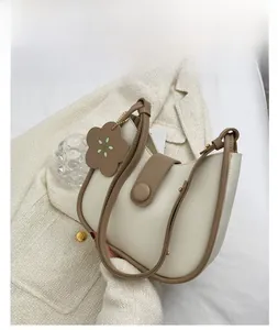 Detail of a khaki contrast half-moon bucket bag with a decorative floral charm and round buckle