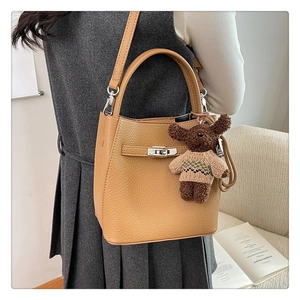 Détail du sac seau en cuir grainé marron avec fermoir métallique et breloque ourson