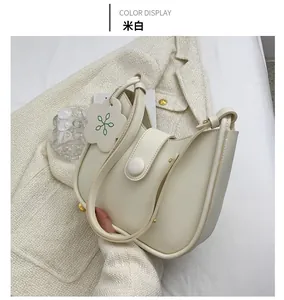Detail of off-white PU saddle bag with floral tag on white tweed jacket