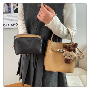Détail du sac seau marron à grain de litchi avec fermoir argenté et charm ours peluche