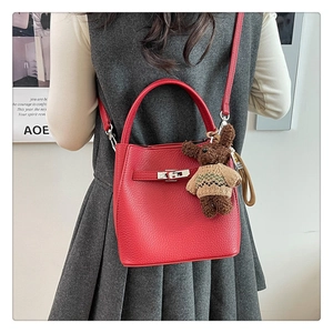 Détail du sac seau en cuir grainé rouge avec boucle métallique et pendentif ours