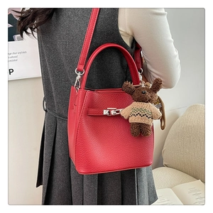 Détail du sac seau en cuir rouge grainé avec fermoir en métal et breloque ours