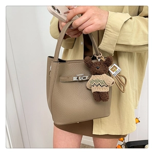 Détail du sac à main en cuir marron avec fermoir métallique et charm ours mignon