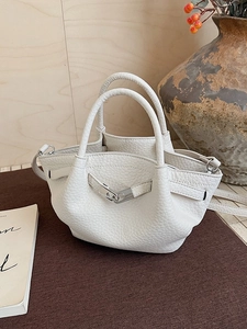 Elegant white litchi pattern leather bucket bag with silver lock on a brown textile surface