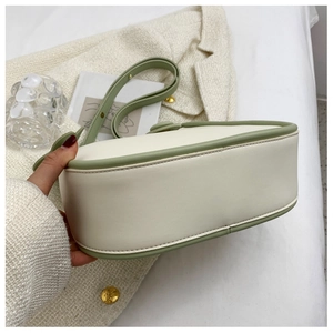 Detailed view of cream leather saddle bag with sage green trim and premium stitching