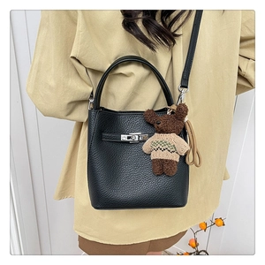 Détail du sac seau noir en cuir grainé avec boucle argentée et breloque ours en peluche