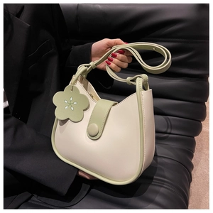 Detail of color-block crescent bag with cream leather and green trim and floral charm