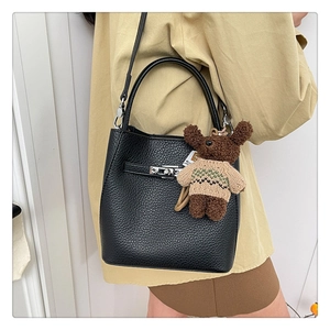 Détail du sac seau en cuir grainé noir avec serrure argentée et breloque ourson