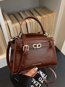 Elegante borsa a mano marrone scuro lucido con finiture dorate in scena lifestyle