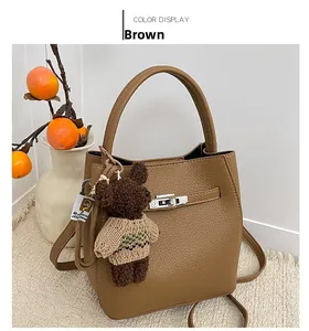 Gros plan du sac seau en cuir marron avec charm ours et fermoir métallique brillant