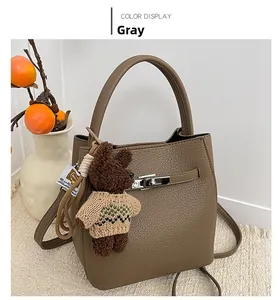 Détail du sac seau en cuir gris texturé avec fermoir métallique et breloque ours