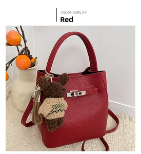 Détail du sac seau rouge en cuir grainé avec fermoir Kelly et pendentif ours en peluche