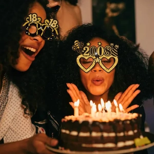 Close-up of sparkling black and gold glitter birthday glasses for milestone party