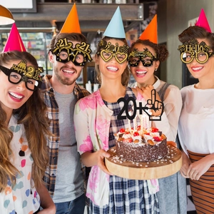 Close-up of 21st birthday party glasses and cake topper in black and gold glitter