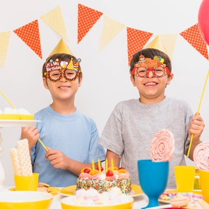 Kids wearing Happy Birthday party glasses with donut and balloon decorations in a festive scene