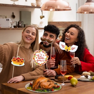 Group of friends using Thanksgiving photo props like pumpkin pie and signs at dinner