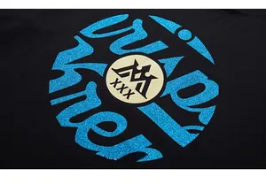 Détail de l'imprimé rond pailleté bleu et logo couronne sur t-shirt noir en coton oversize