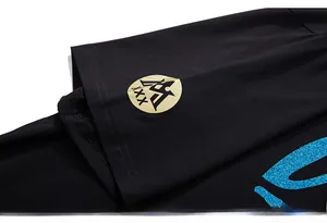 Gros plan du logo doré et de l'imprimé pailleté bleu sur le t-shirt en coton noir