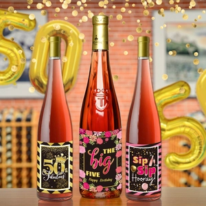 Detail of 50th birthday wine bottle labels with gold text on a festive party background