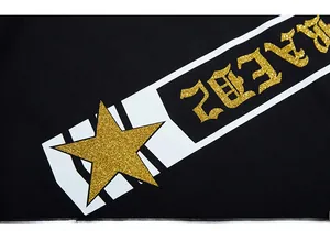 Macro detail of gold glitter star and gothic lettering print on black cotton fabric