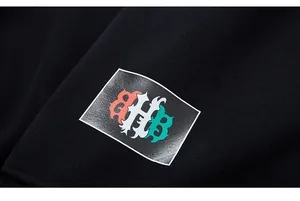 Macro detail of gothic style orange and green letter printing on black knit sweatshirt