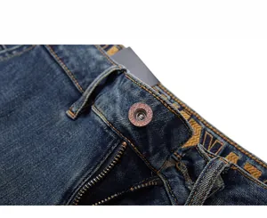 Detail shot of heavy-duty washed denim jeans waist with metal button and zipper