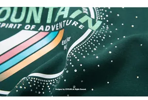 Macro shot of dark green sweatshirt fabric with rhinestone mountain print detail