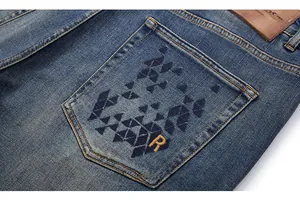 Detail of vintage blue jeans showing back pocket with geometric embroidery and leather patch