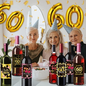 Detail view of 60th birthday wine bottle labels in black gold and pink party setting