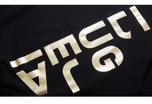 Macro view of metallic gold letter printing on black knitted fabric sweatshirt