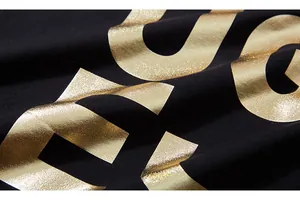 Close-up of premium metallic gold foil letter printing on black cotton sweatshirt fabric