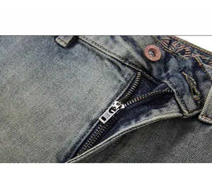 Detail of high-quality YKK metal zipper and bronze button on washed blue vintage jeans